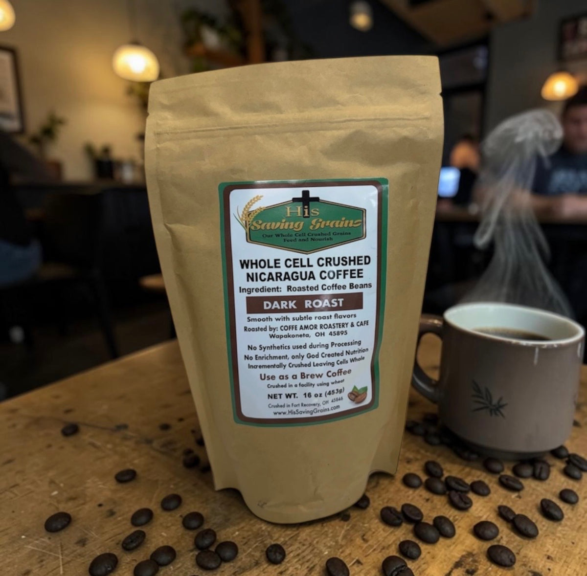 Coffee package with a label on a wooden table with coffee beans and a cup in a blurred cafe setting